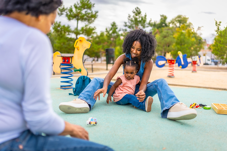 little-girl-and-mother-playing-car-toys-with-grand-2024-12-10-03-08-44-utc Family bonding at a park, supporting social skills through community-based ABA therapy in San Fernando Valley.